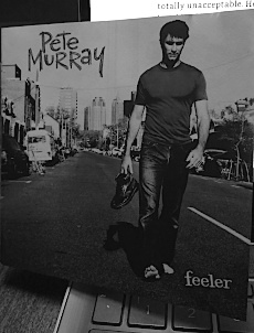 An old black and white photograph of some douchey white dude walking down the middle of the road (somewhere in Brisbane I believe) trying to look all thoughtful and creative and shit. He's not wearing any shoes and yet he's carrying a perfectly good pair of Doc Martens.