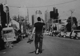 An old black and white photograph of some douchey white dude walking backwards down the middle of the road trying to look all thoughtful and creative and shit. He's not wearing any shoes and yet he's carrying a perfectly good pair of Doc Martens, while scratching the back of his head.